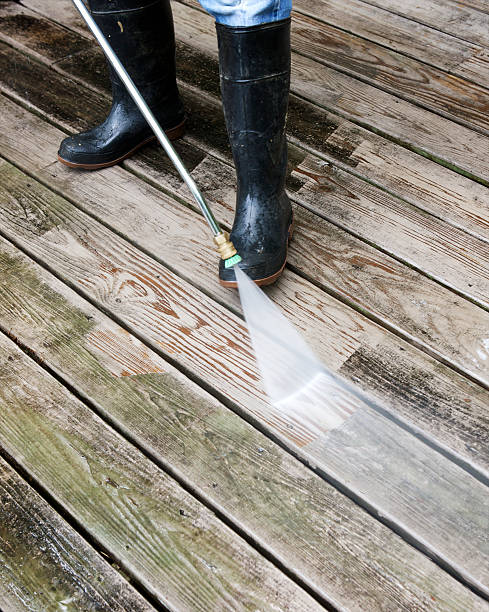 Man pressure washing wooden deck. Vertical shot.